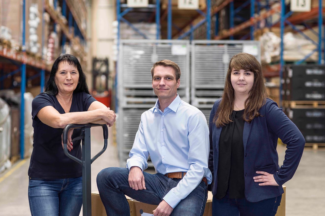 3 Personen vor Logistikhalle