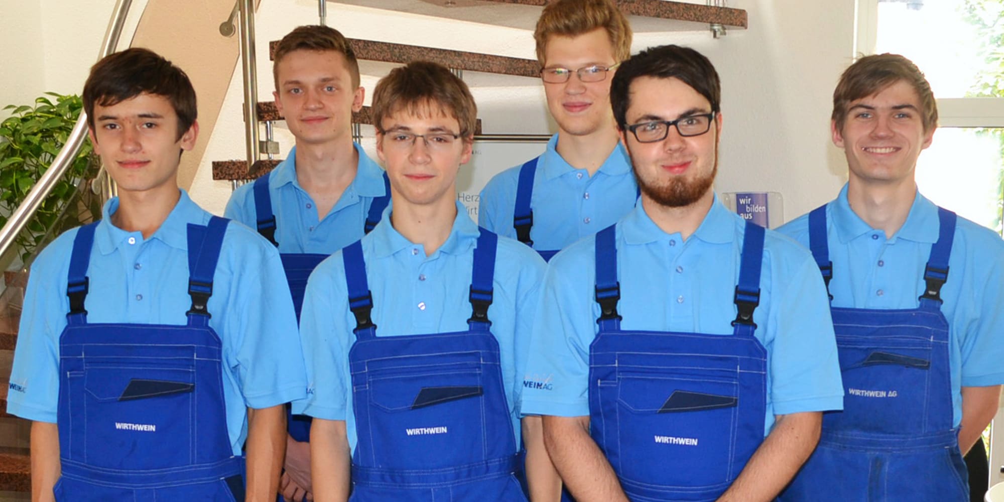 6 Auszubildende in Arbeitskleidung